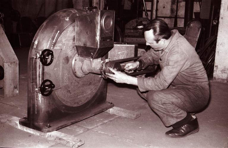 historische Ansicht eines Mechanikers, der eine Riemenscheibe an einer Mühle montiert 